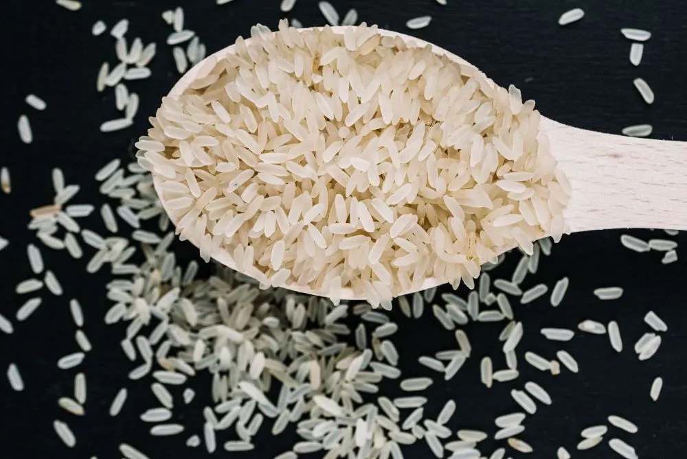 Riz étuvé dans une cuillère en bois sur fond noir